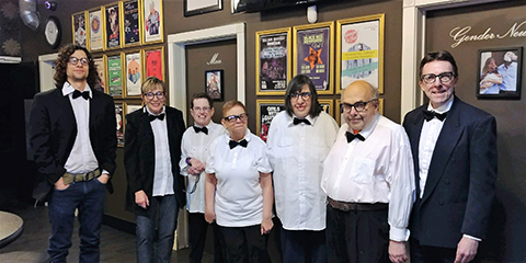 A group of seven people wearing white shirts and black bow ties at the West End Cultural Centre