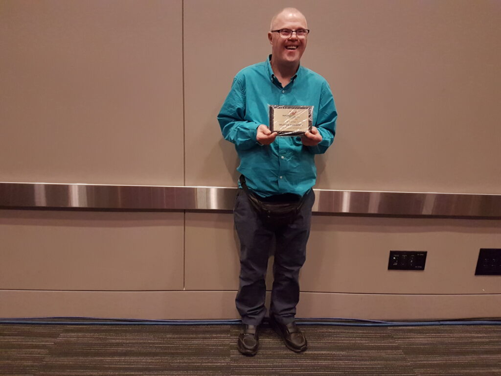 A person named Wilf smiling while receiving a 30 year award