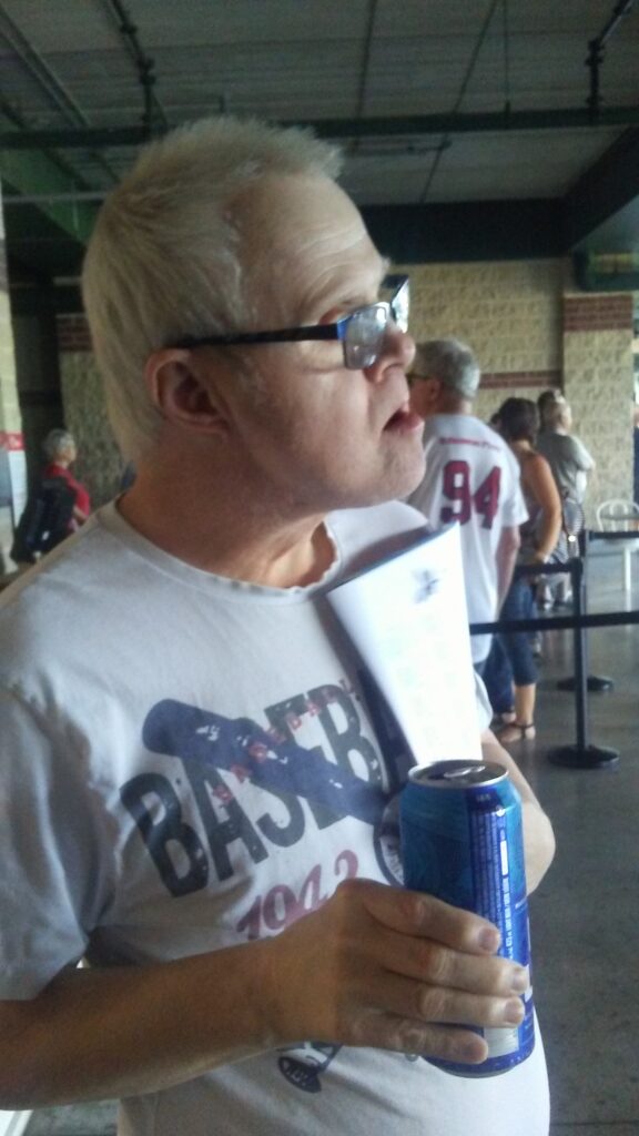 A person named Wilf holding a canned beverage while a Goldeyes baseball game