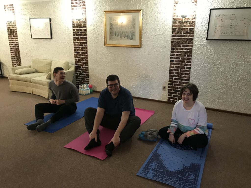 Three people sitting on the floor on yoga mats